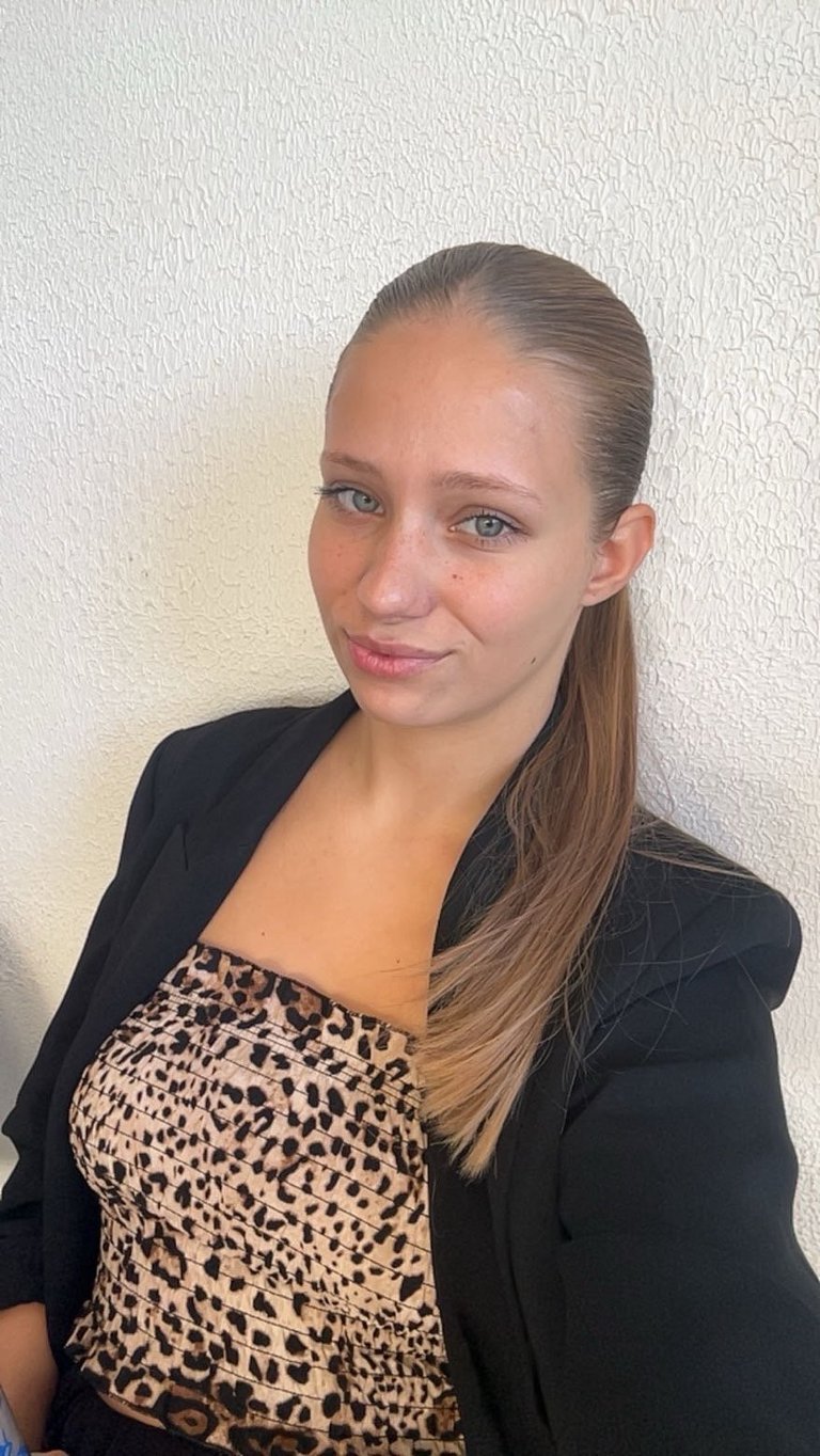 Woman wearing a black blazer over a leopard print top against a white textured wall